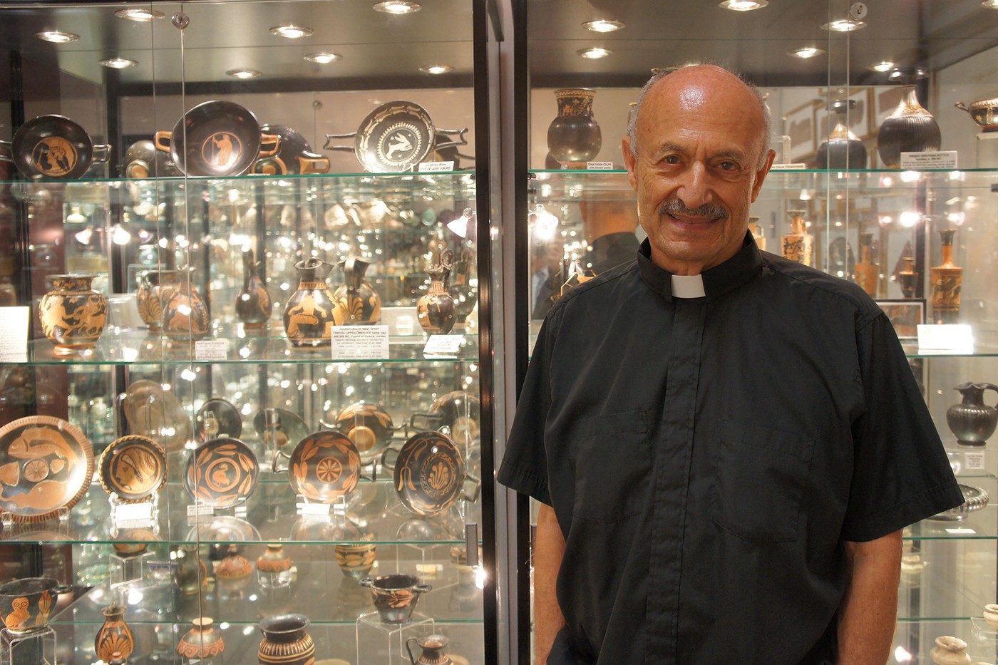 priest stands in front of display cases